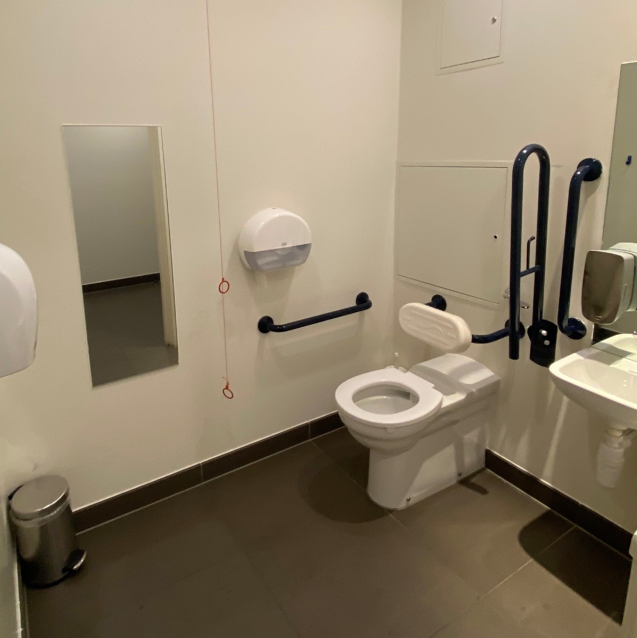 View of the accessible toilet with toilet, sink, mirror and hand dryer