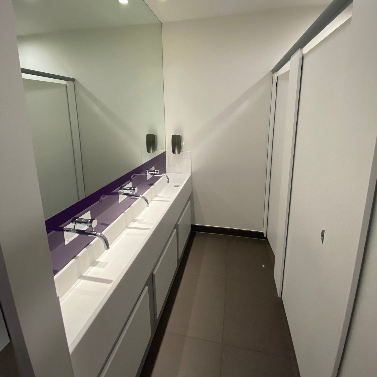 View of women's toilet showing sinks, mirror and cubicles
