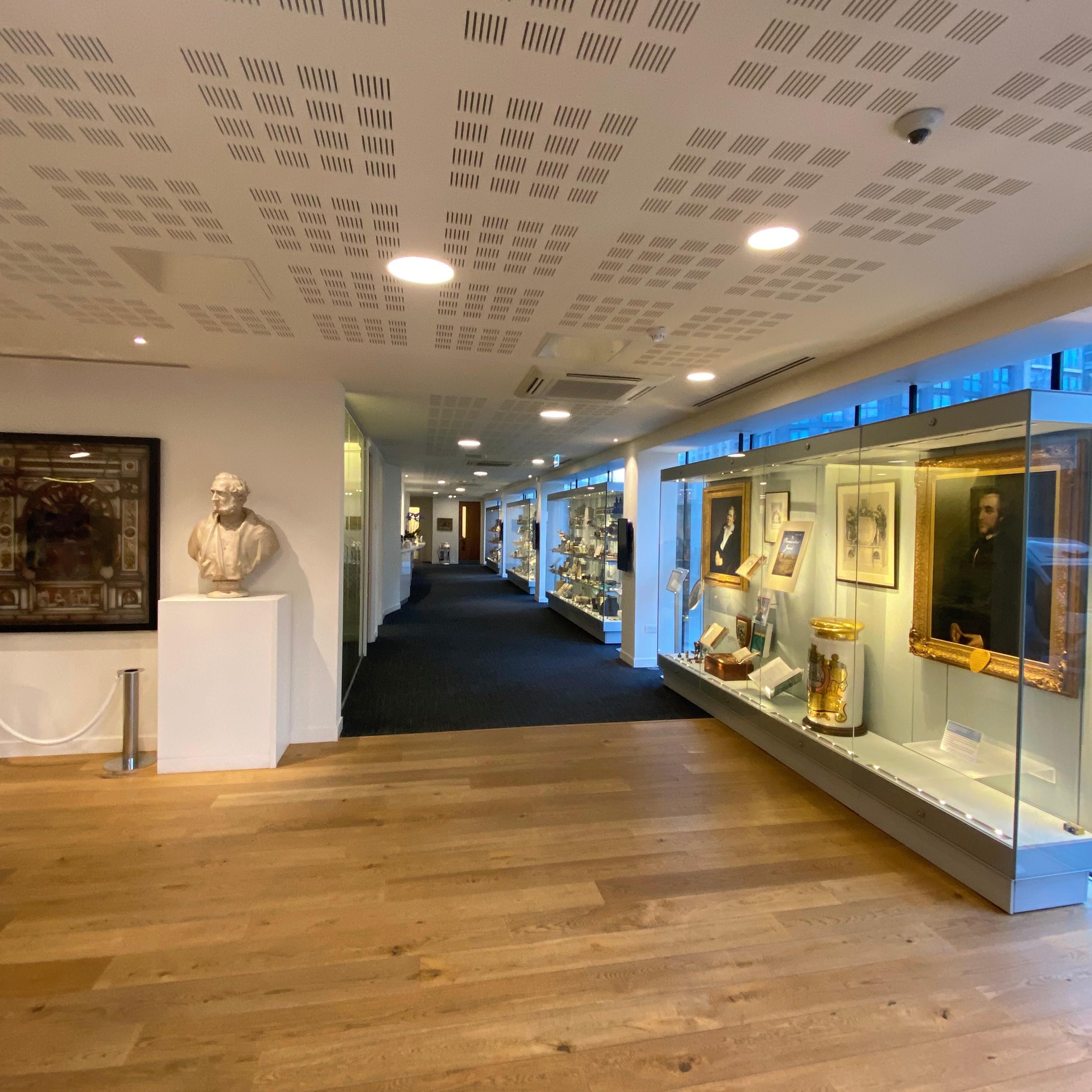 Museum Section three corridor with bust and display cases. Image shows a section where wooden floor changes to carpeted floor